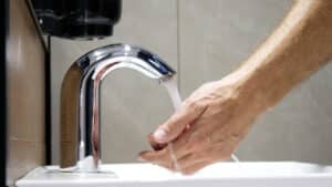 Touchless faucet and a man washing his hands, Smart Plumbing Automation.
