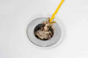 Unexpected Causes of Clogged Drain Lines 1 Cleaning hair and soap scum from clogged shower and bathtub drain, Clogged Drain Lines.