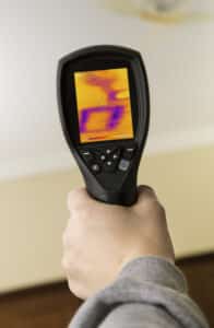 A homes ceiling with a leaking pipe and inspector looking at the damage through a thermal imaging camera, Hidden Water Leaks.