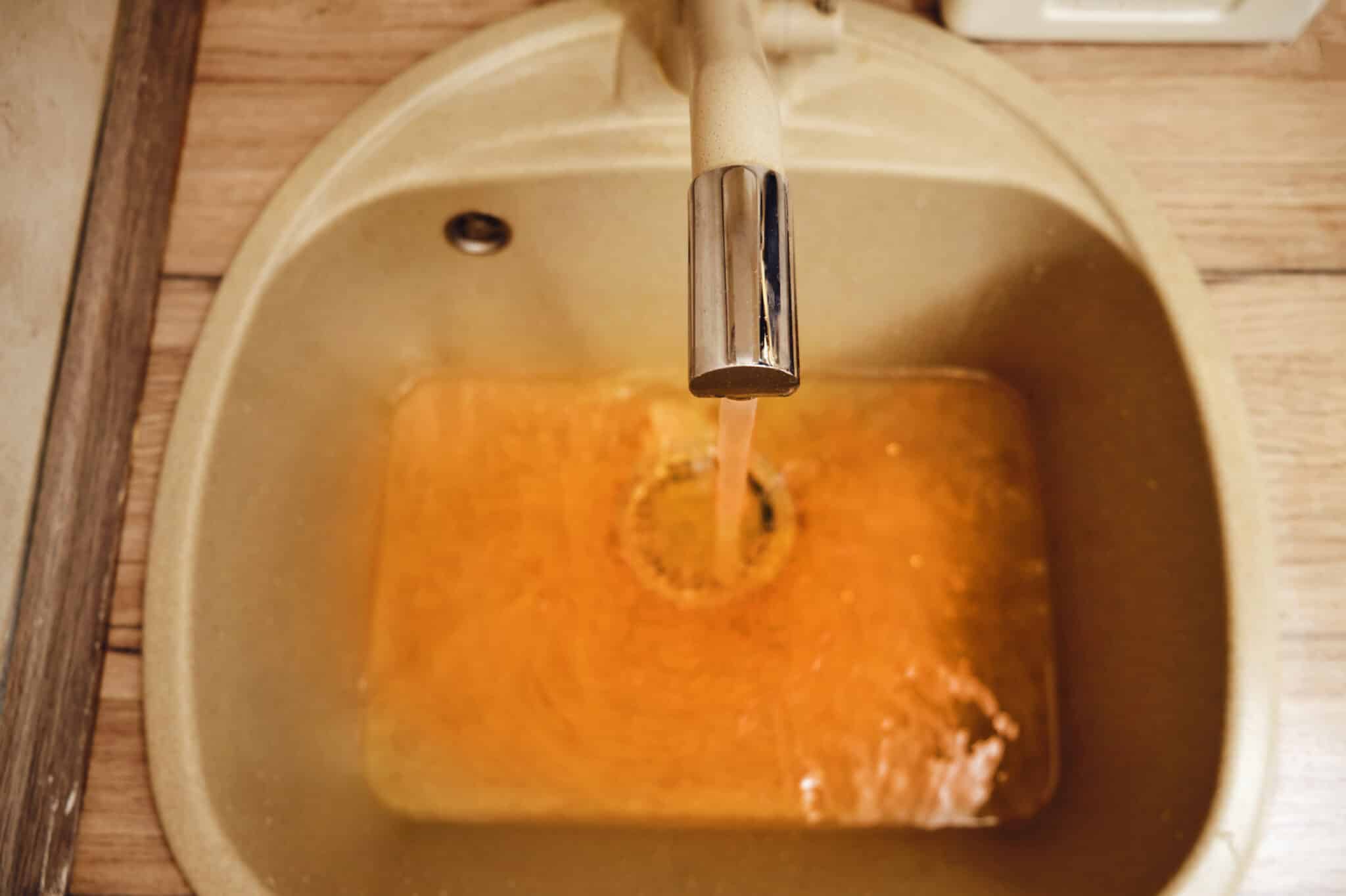 Rusty water flows from the tap into the sink in the home kitchen, anode rod replacement.