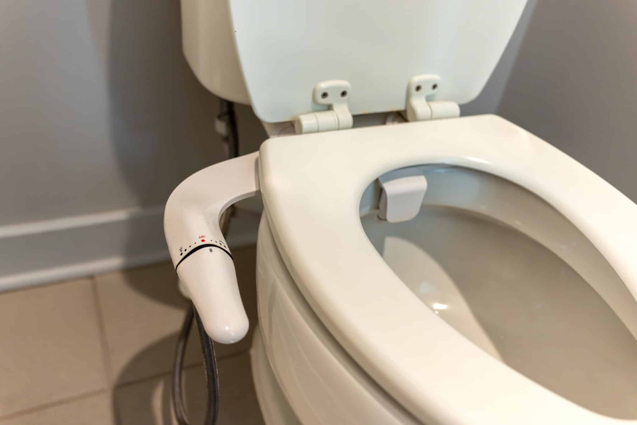 Bidet attachment on a modern toilet in a home restroom, bidet seat setup.