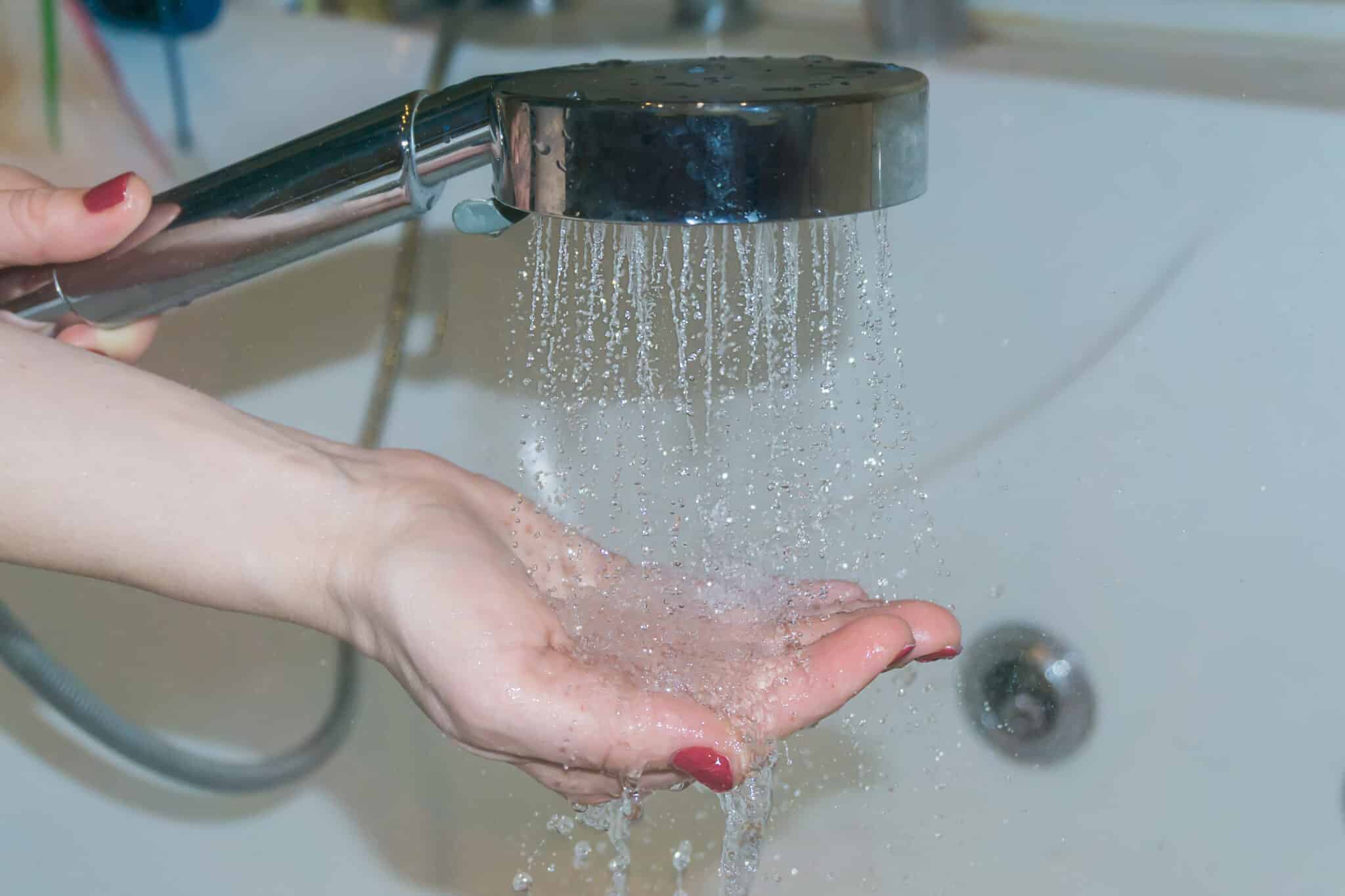 Heating element failures during cold winter months 1 Woman's hand checking water temperature condition in the shower, heating element failures.