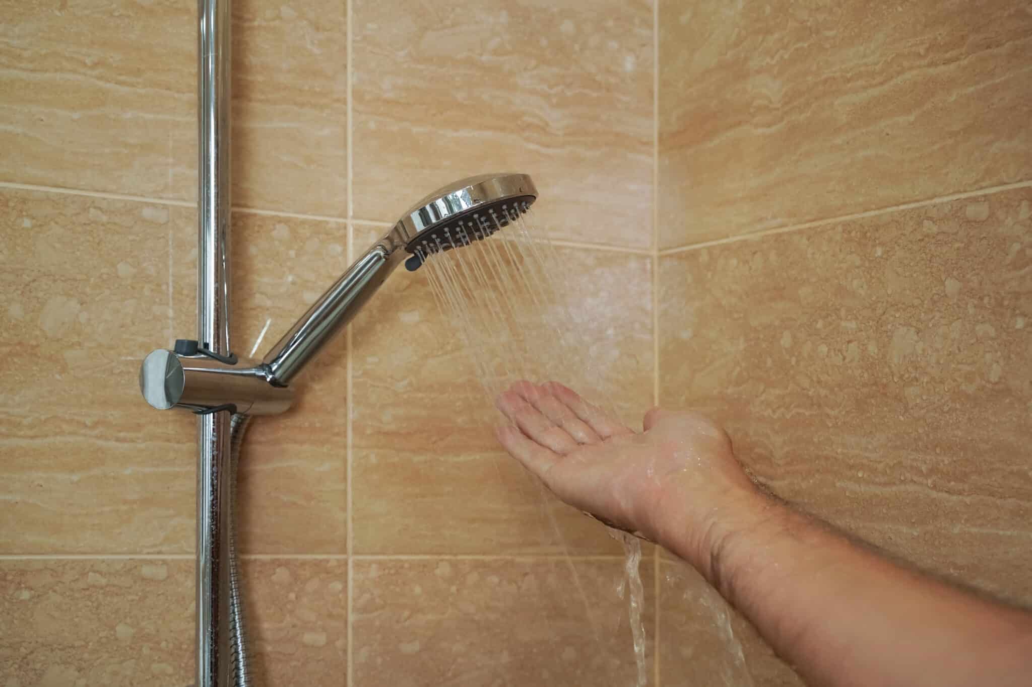 A plumber checks the temperature of the water in the shower faucet in the bathroom, recirculation bypass valve.
